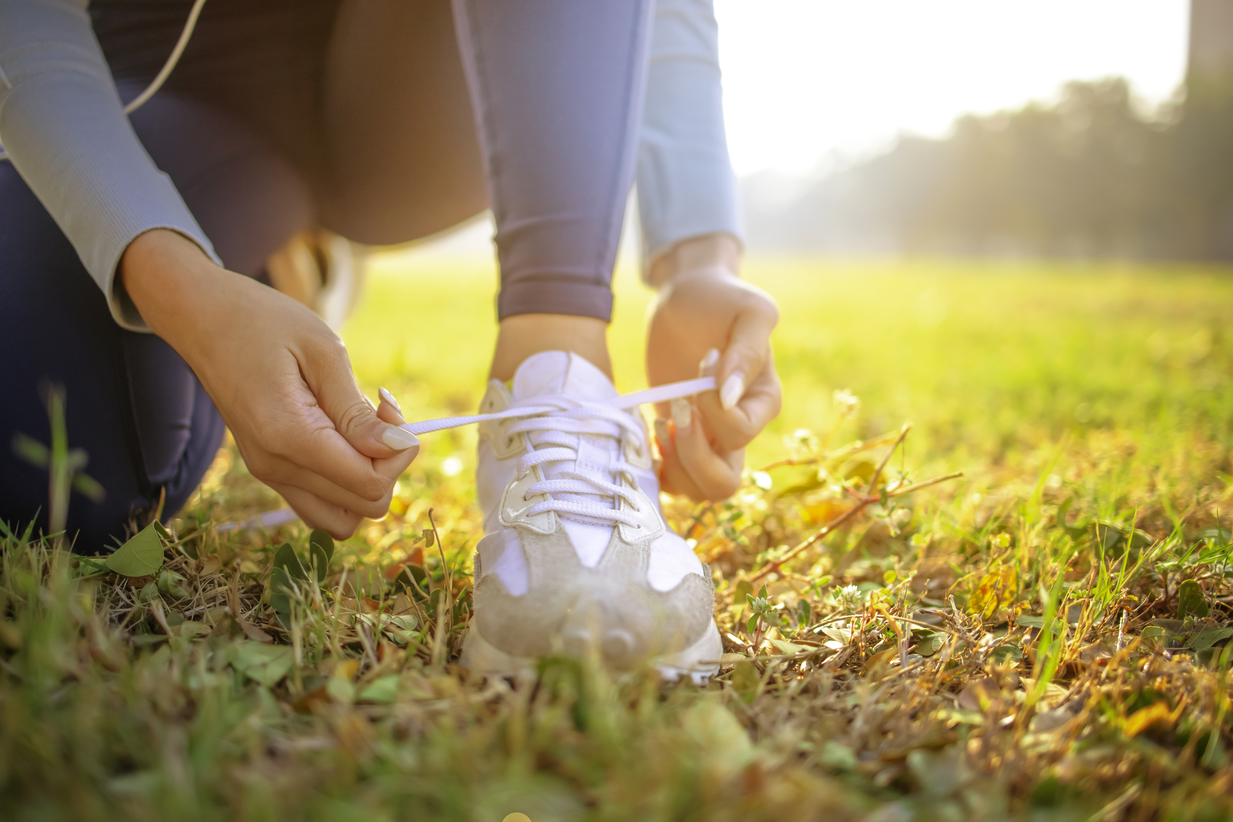 Women tying shoe on bright sunny day.