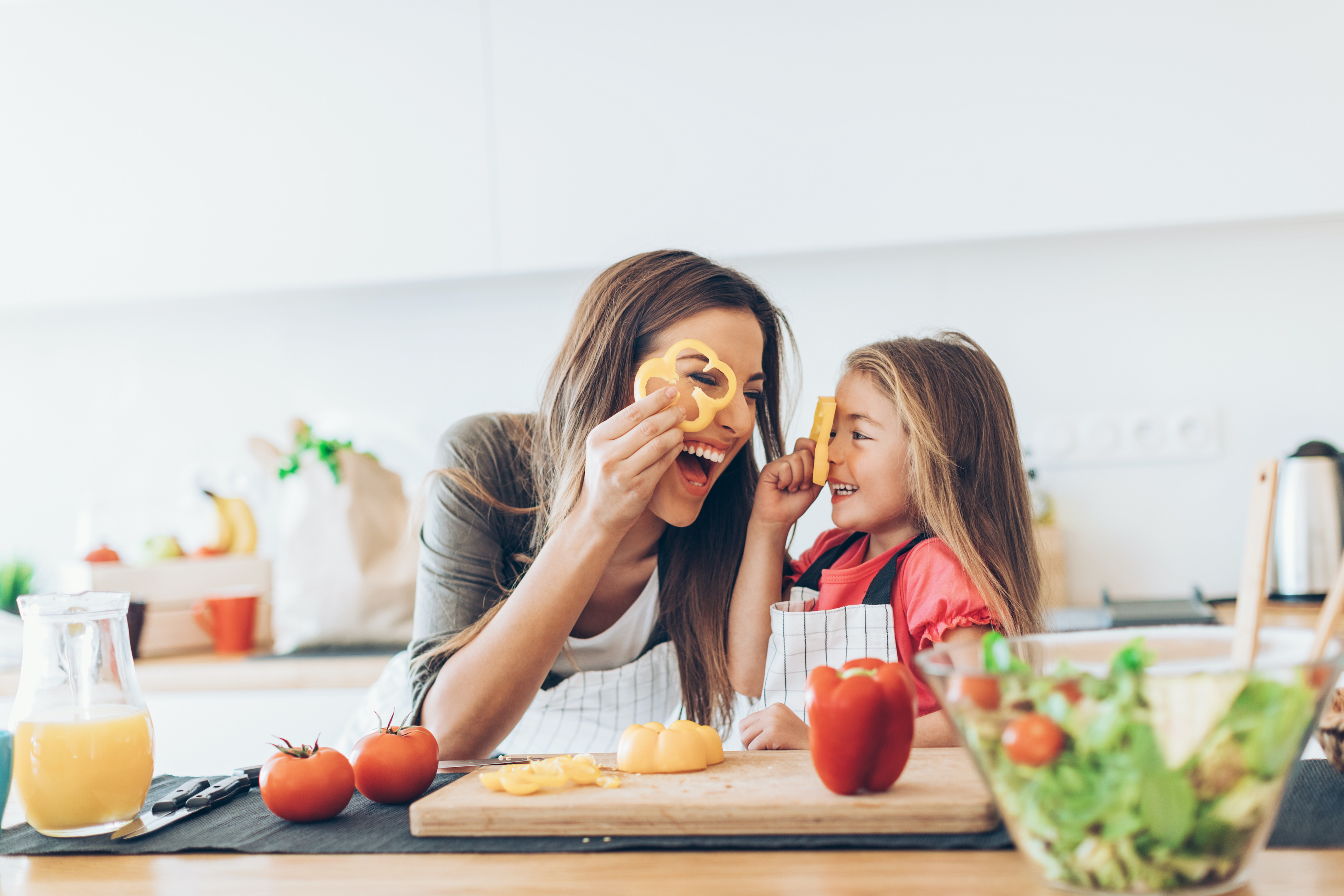 Woman laughing with her daughter as they prepare a meal.