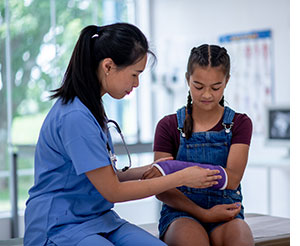 Female doctor examining broken arm of young girl.
