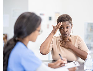 Woman explaining headache to doctor.